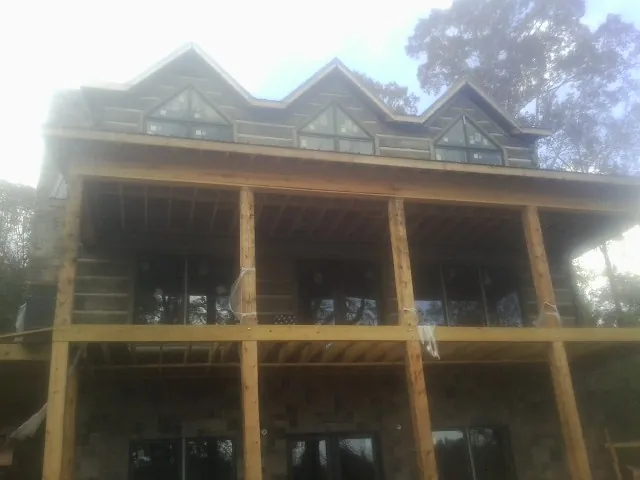 Dormers and porch framing on a large log home under construction — Roof Coating work by our crew in Hooven