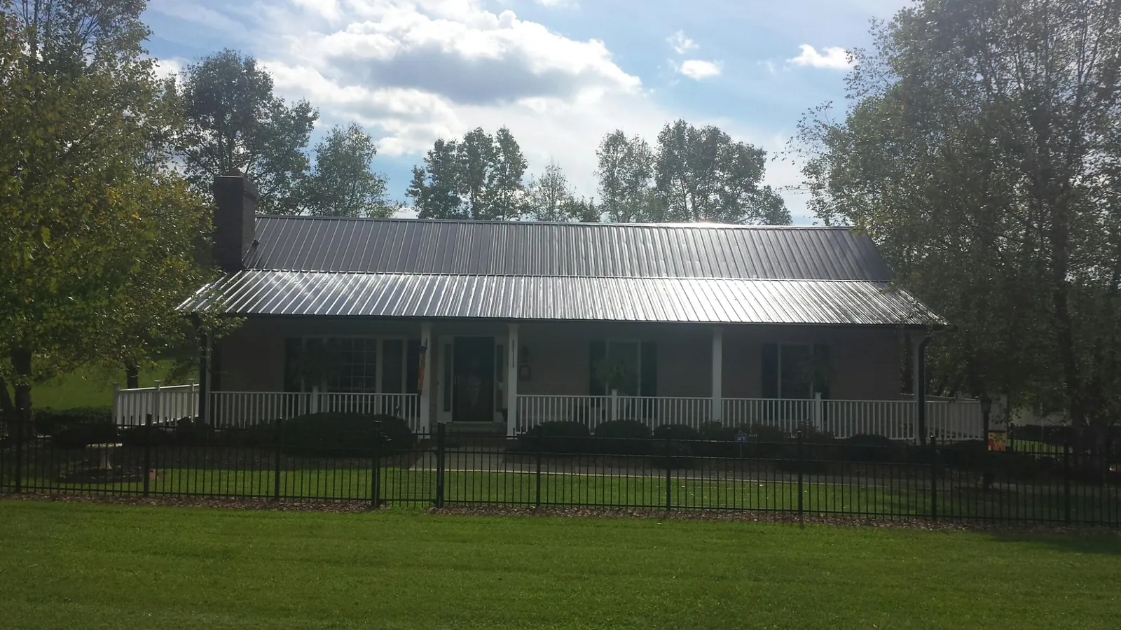 Gray metal roof on a brick ranch with a full width front porch — Gutter Guard Installation work by our crew in Hooven