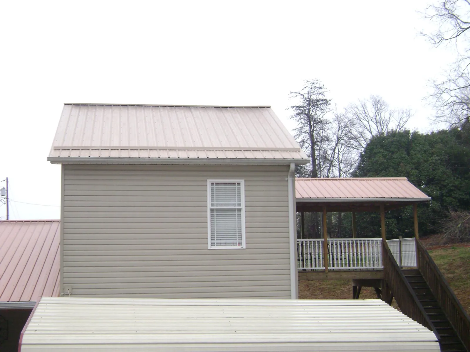 Tan metal roofs on a two story addition and attached porch, from a Roof Replacement job in Hooven