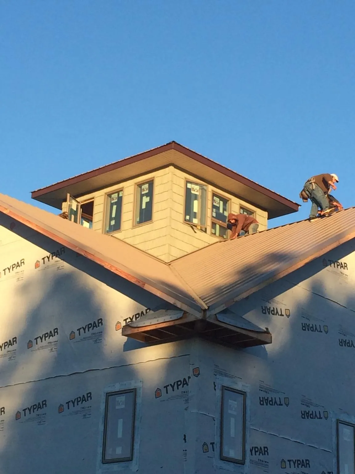Roofers working around a rooftop cupola on a new metal roof at sunset — Roof Waterproofing in Hooven by Roofing Brothers